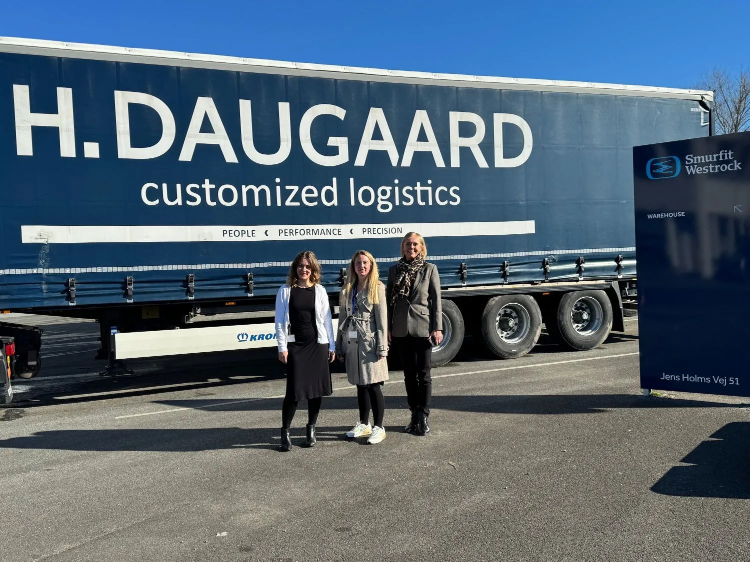 Tre kvinder foran en lastbil, hvor der står Daugaard på