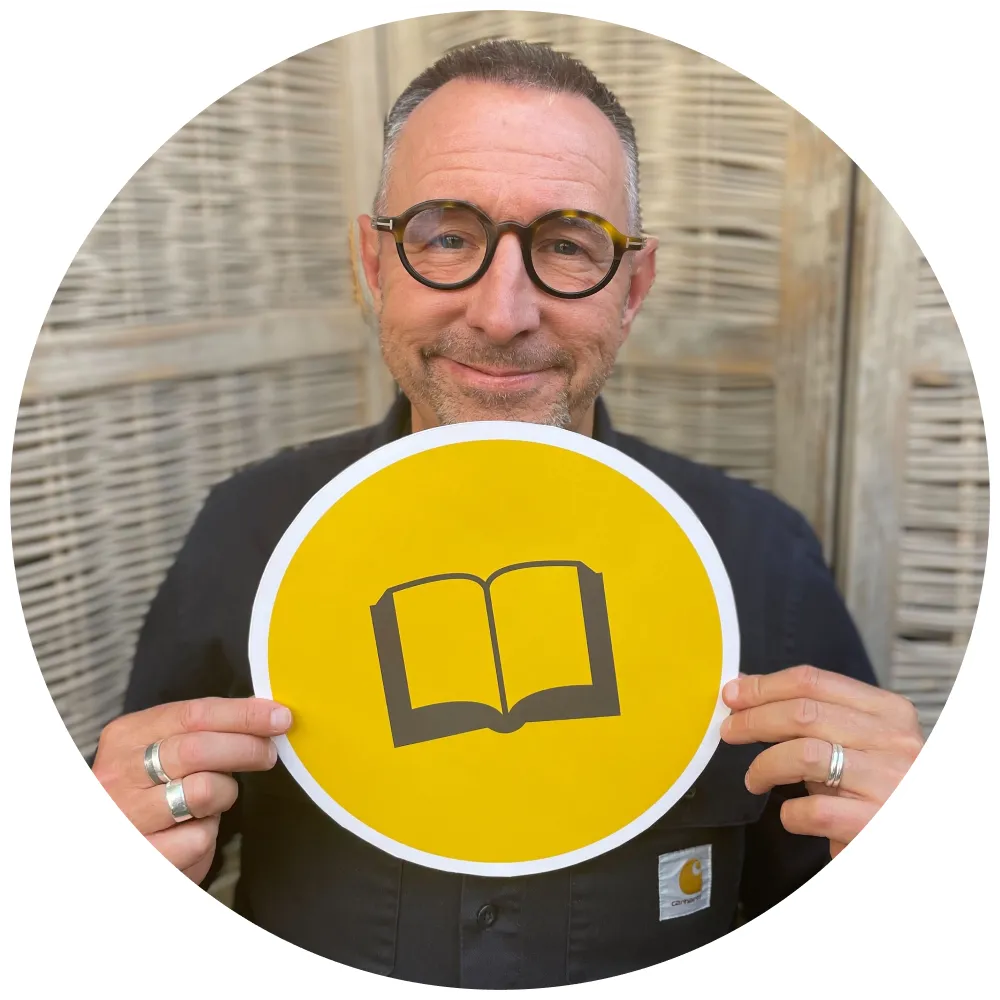Podcast host Chris Grimes holding yellow Good Books podcast sign