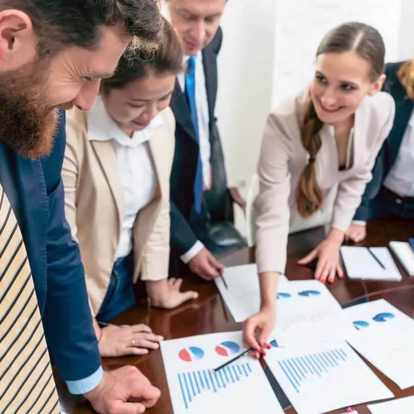 Business team gathered around a table reviewing charts and graphs during a meeting.
