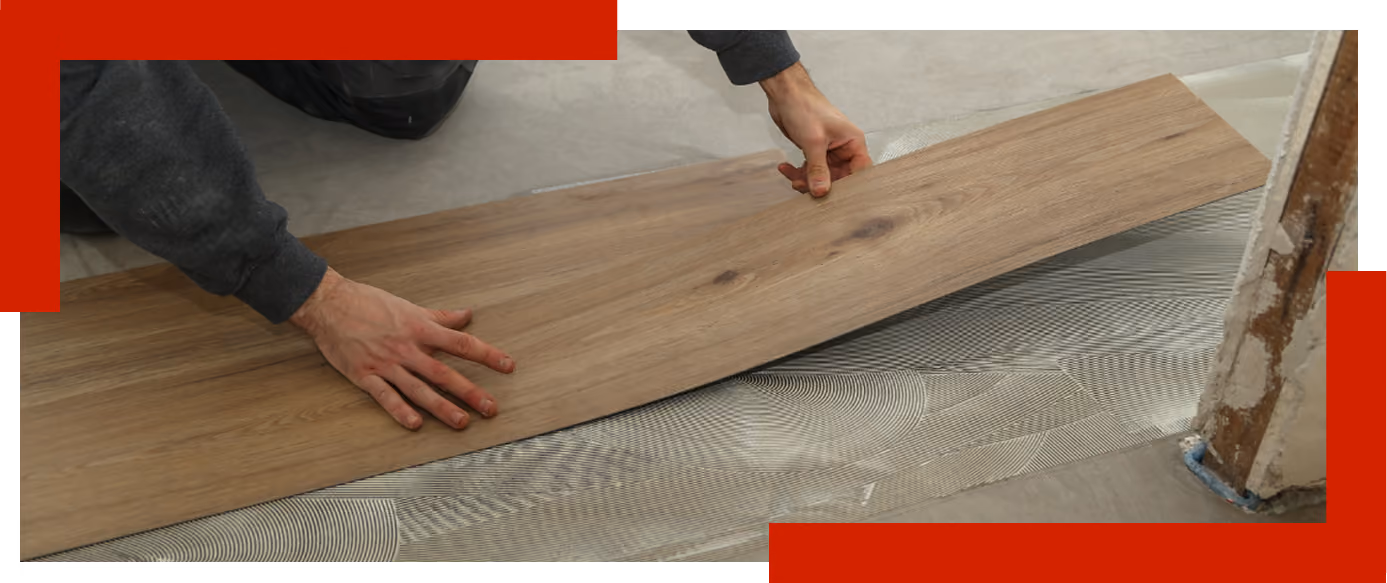 Person verlegt Holzlaminat auf den Boden über Kleber oder Unterlage.