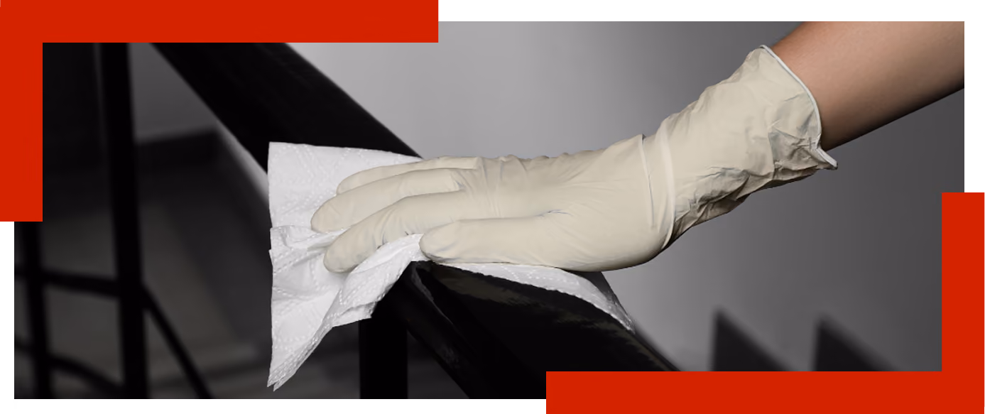 Hand wearing a latex glove cleaning a black metal railing with a white cloth.