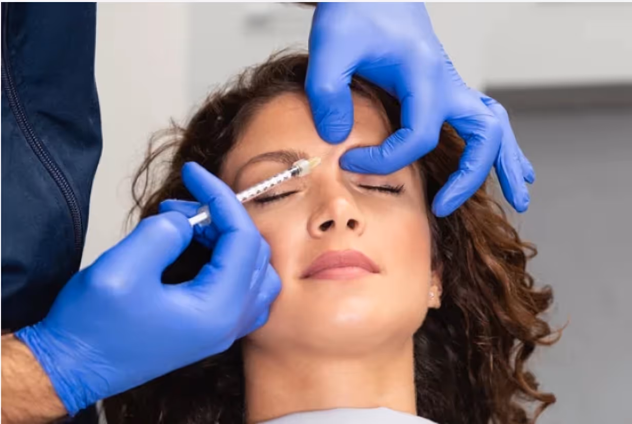 Doctor performing Botox injection into the glabella area to treat frown lines.