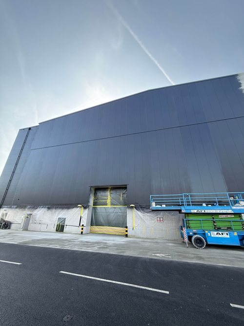 Final inspection of the spray-painted cladding before signage installation.