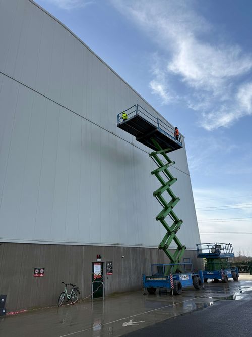 Boom lift reaching high areas for precise spray painting application.