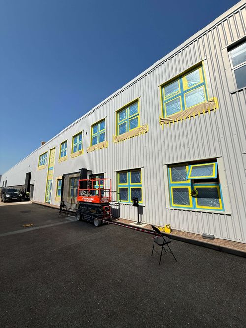 Blue window frames masked off against grey corrugated sheeting.