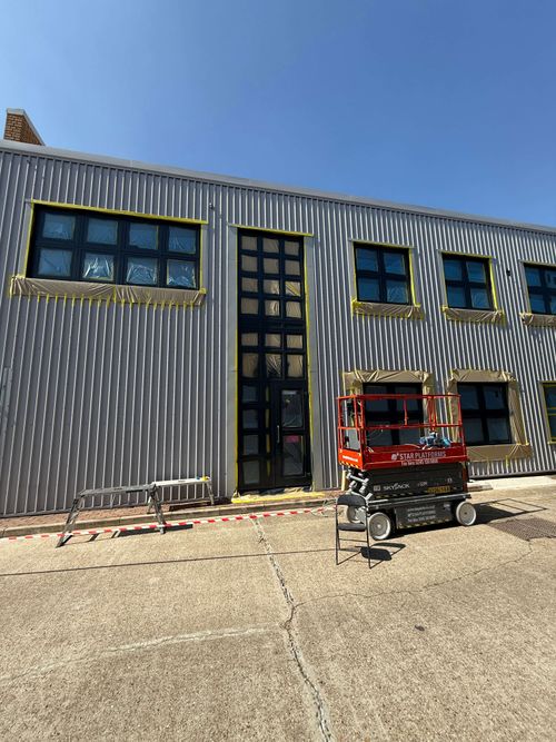 Wide view of fully masked commercial facade ready for spraying.