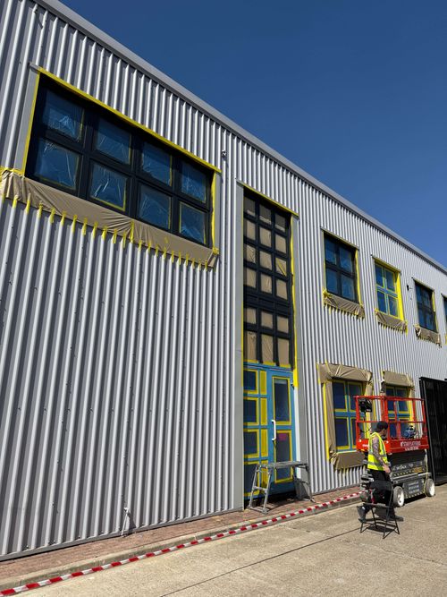 Team preparing facade using platform access and masking film.