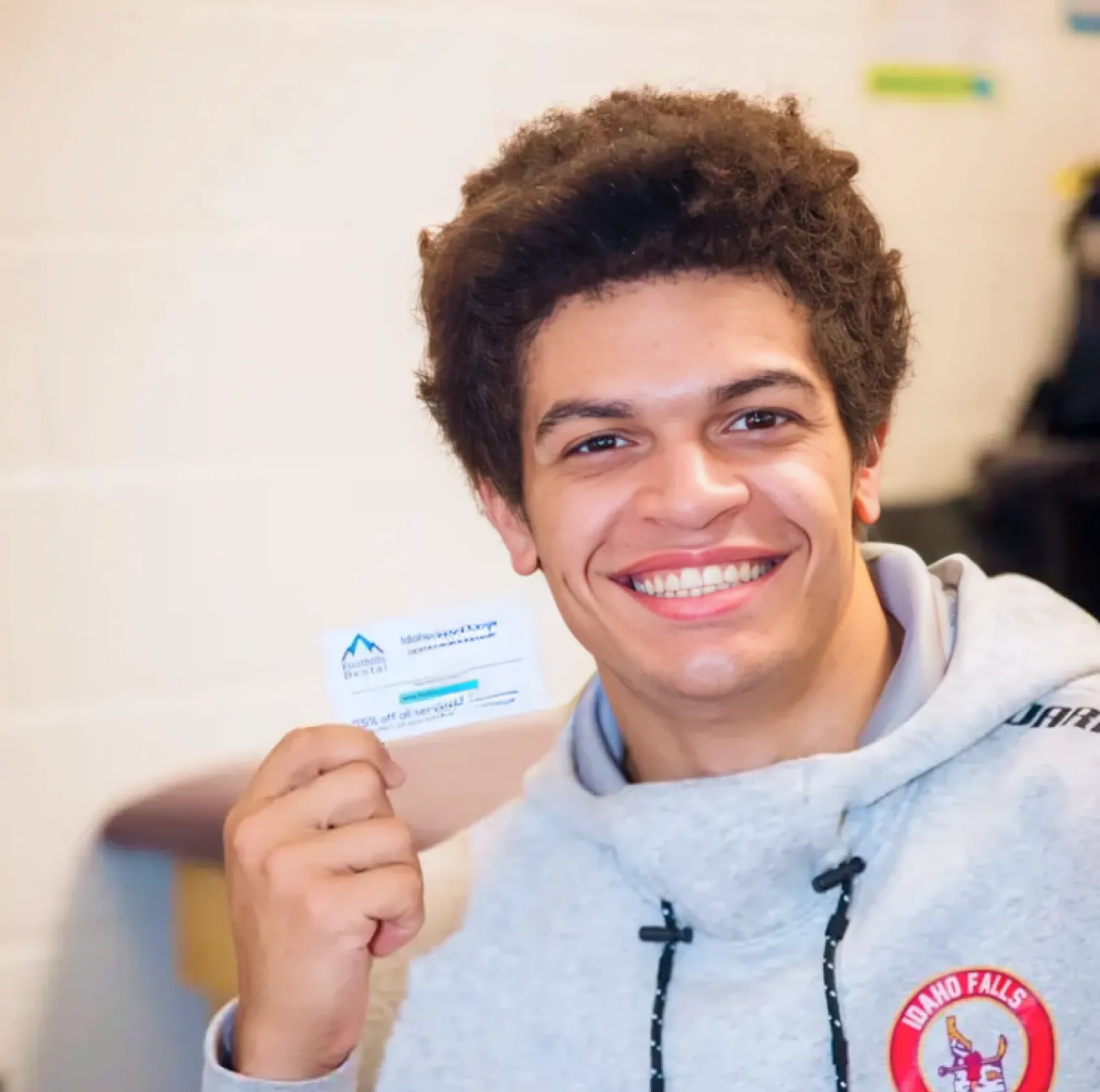 A person smiling and holding up a business card in their hand.