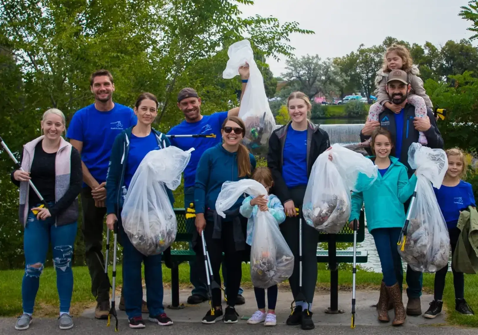 A group of volunteers holding trash bags after cleaning up a park area.