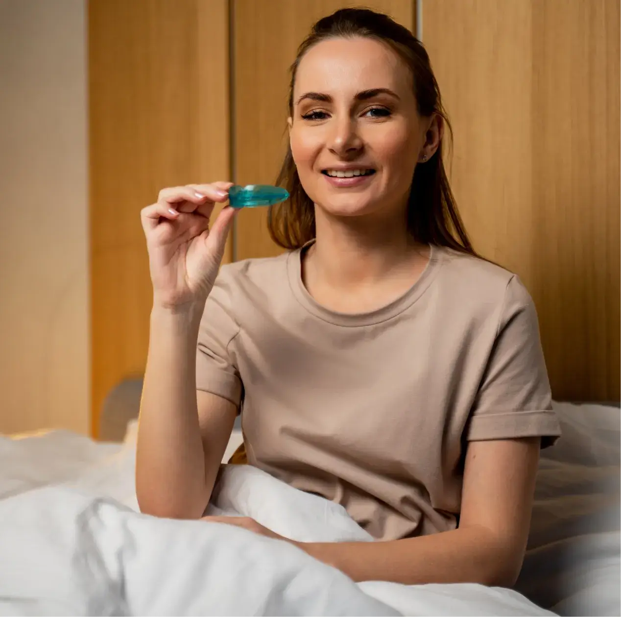 Woman holding nightguards while sitting in bed