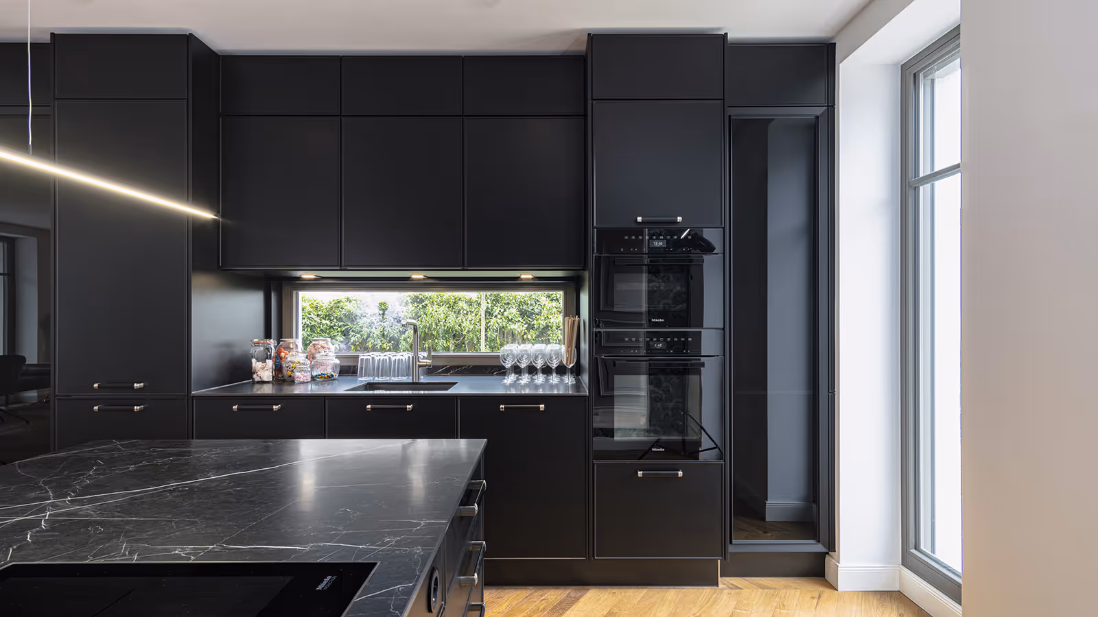 Schwarze Luxusküche mit Fensterfront und eleganter Beleuchtung – Studio 43 Küchenplanung München