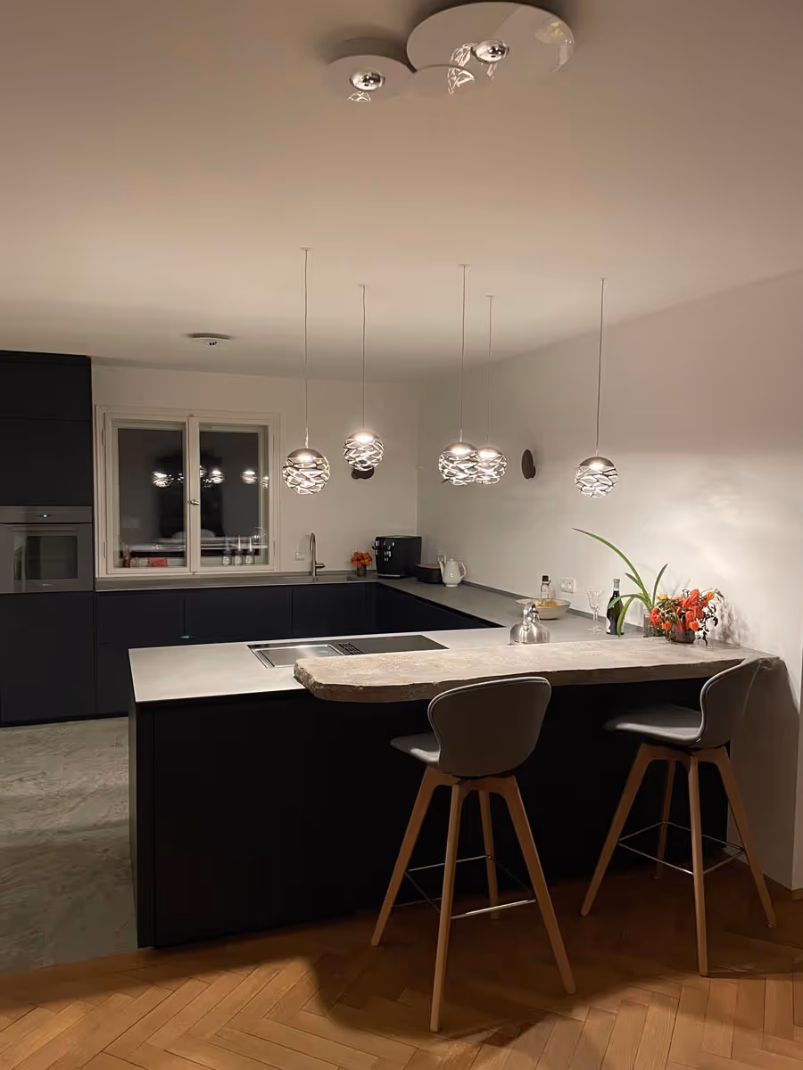 Exklusive offene Küche mit minimalistischen Pendelleuchten und edler Stein-Thekenplatte – Studio 43 München