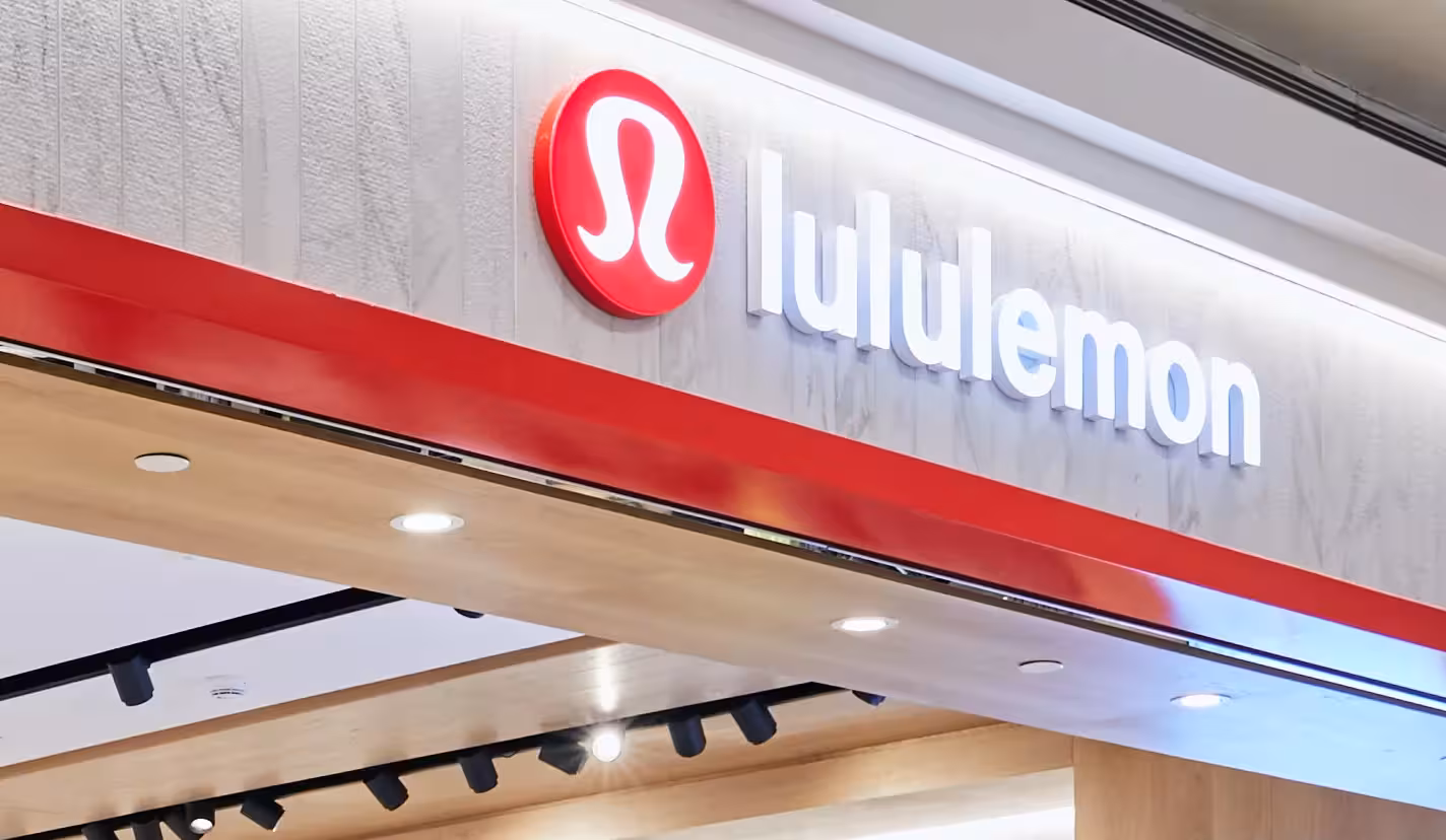 Exterior view of a Lululemon store with a red and white logo on a modern wood and marble facade.