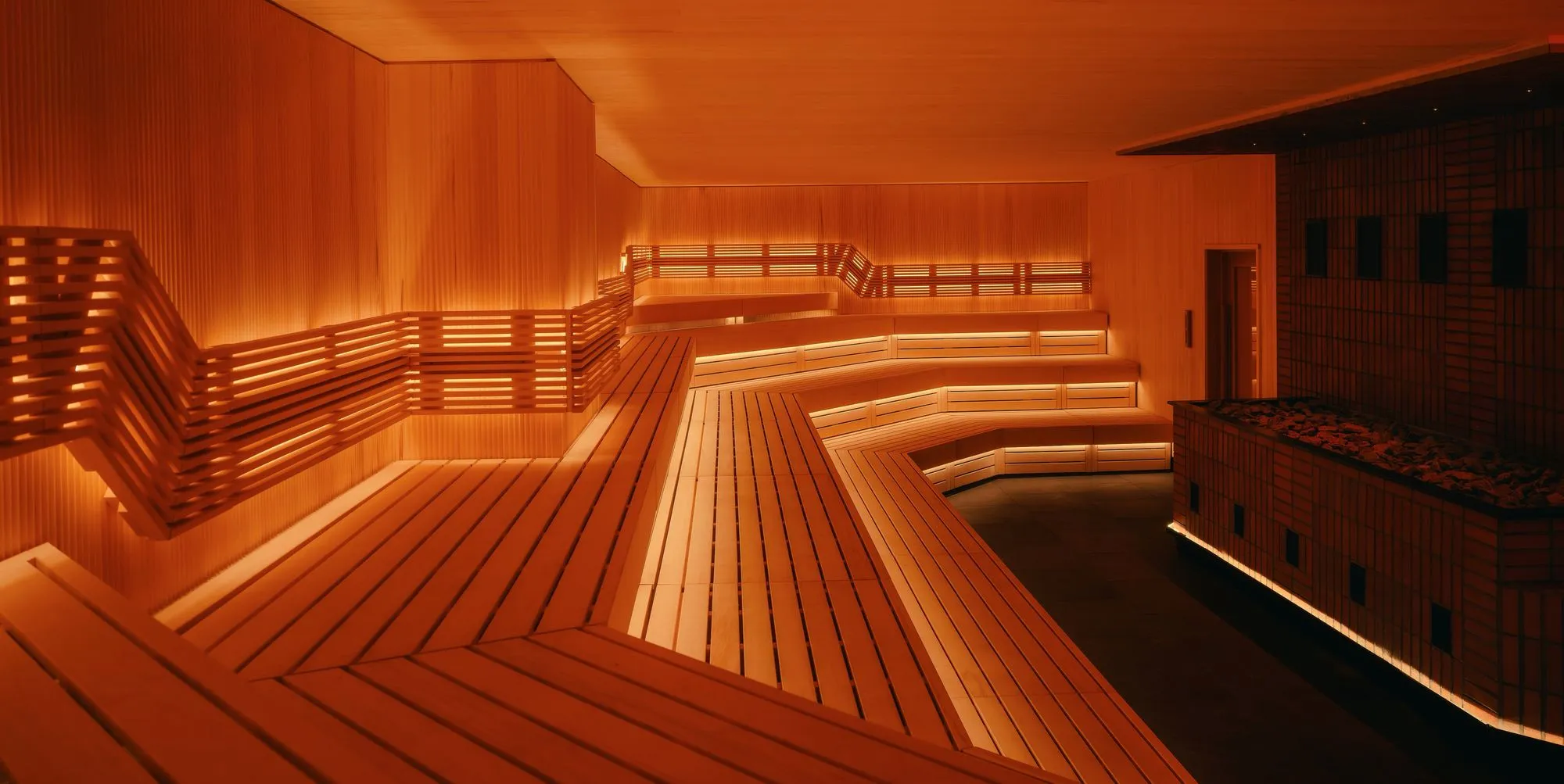 Bright warm sauna with benches and a stove in the middle at Othership Williamsburg