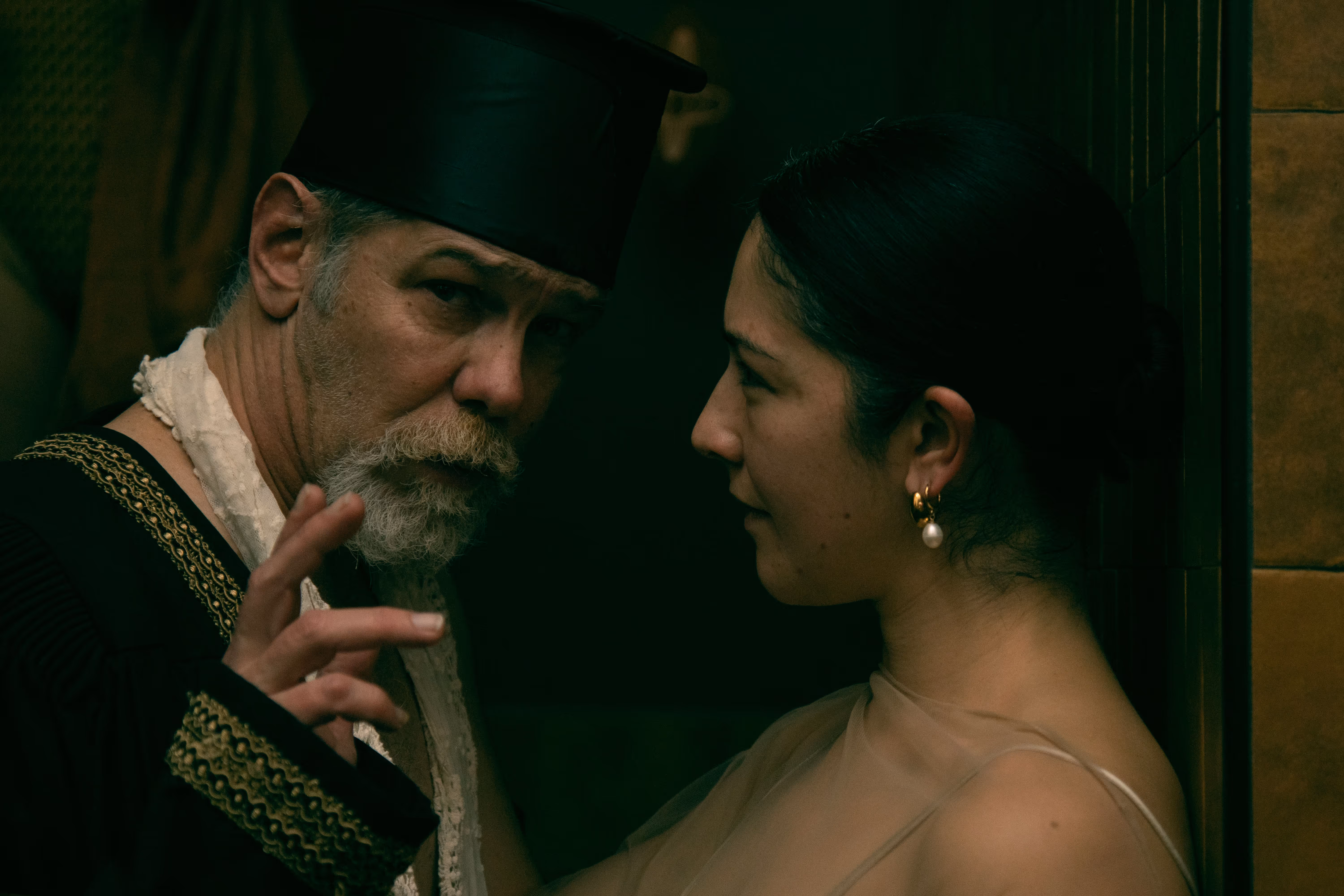 A male cast member in ceremonial costume gestures while facing a female performer during the Rasputin immersive theatre experience at Othership, captured in intimate, low-lit sauna atmosphere.