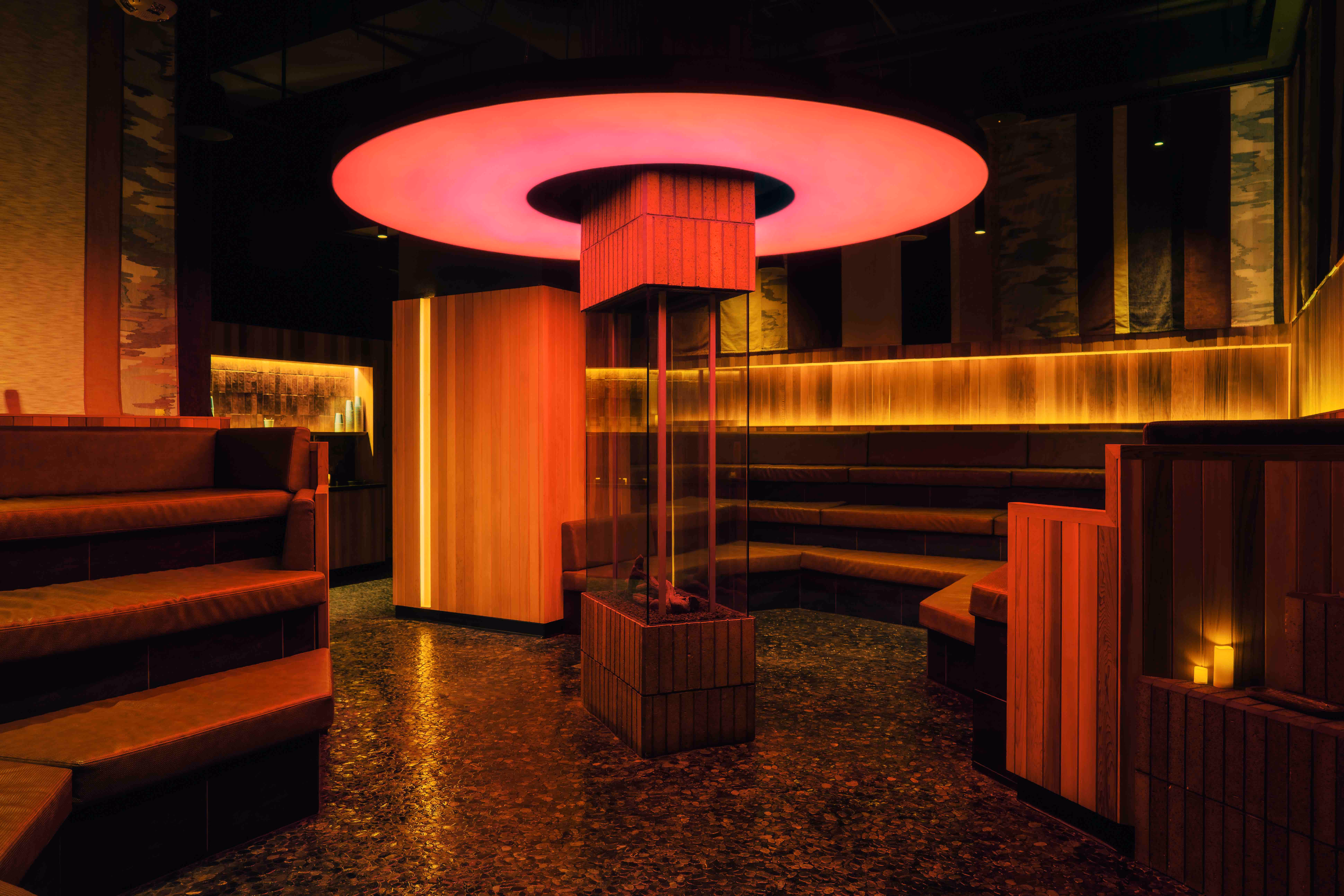 Cozy modern lounge with tiered leather seating and a glowing circular ceiling light fixture.