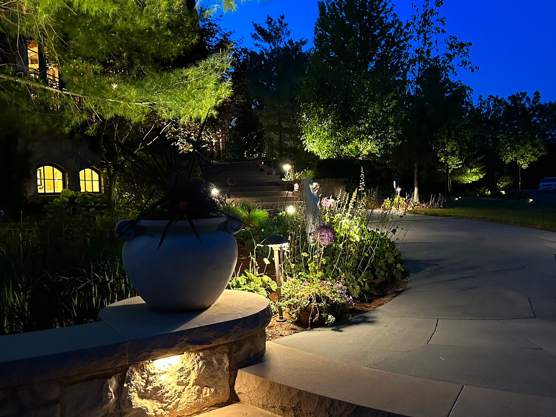 Low-voltage pathlights highlighting layered garden landscape, shrubs, and entry steps in a residential front yard