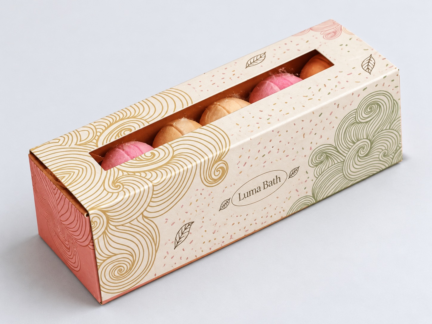 Long cream gift carton with gold patterns and a window showing colorful bath bombs