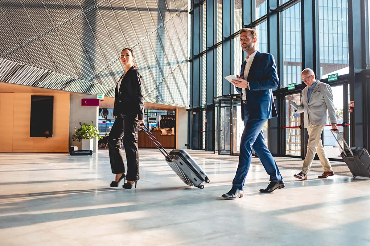 Three business professionals walking through an airport pulling suitcases behind them