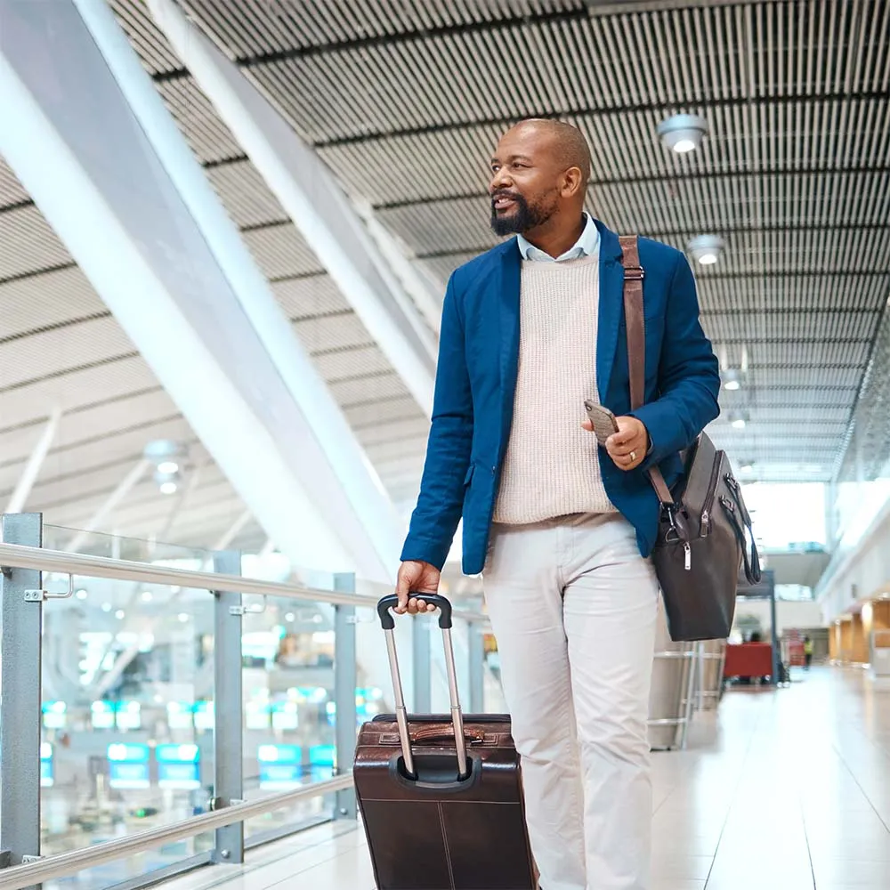 A business man walking through an empty airport pulling a suitcase