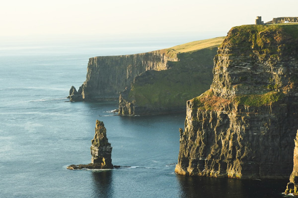 A scenic view off the coast of Ireland with tall cliffs and water below.