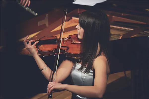 A violinist playing in front of a piano in concert