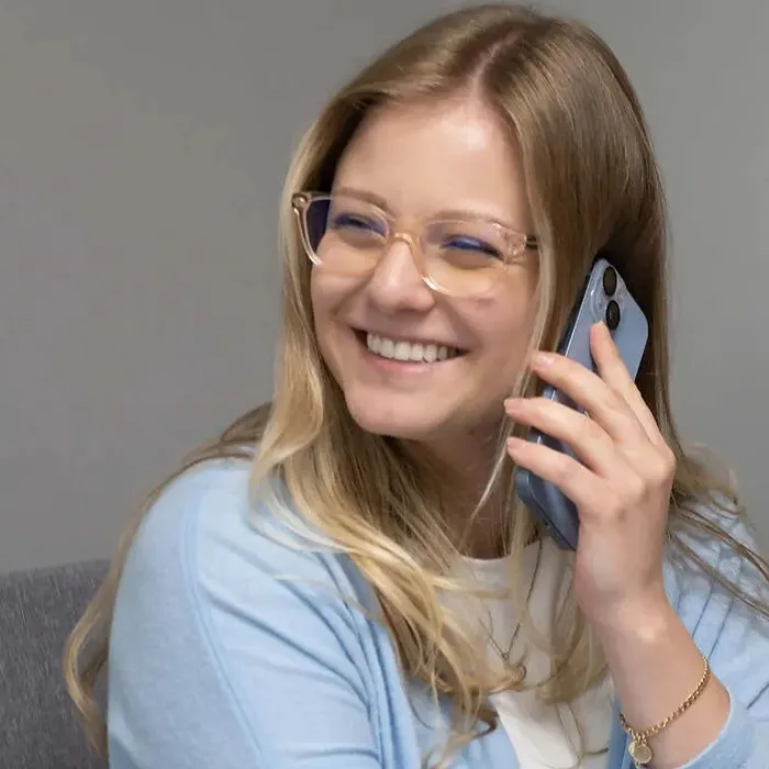 A smiling receptionist holding a phone up to her ear