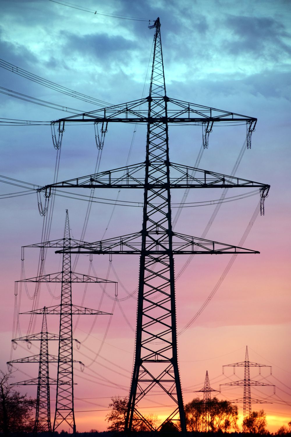 Electricity pylons silhouetted against a sunset