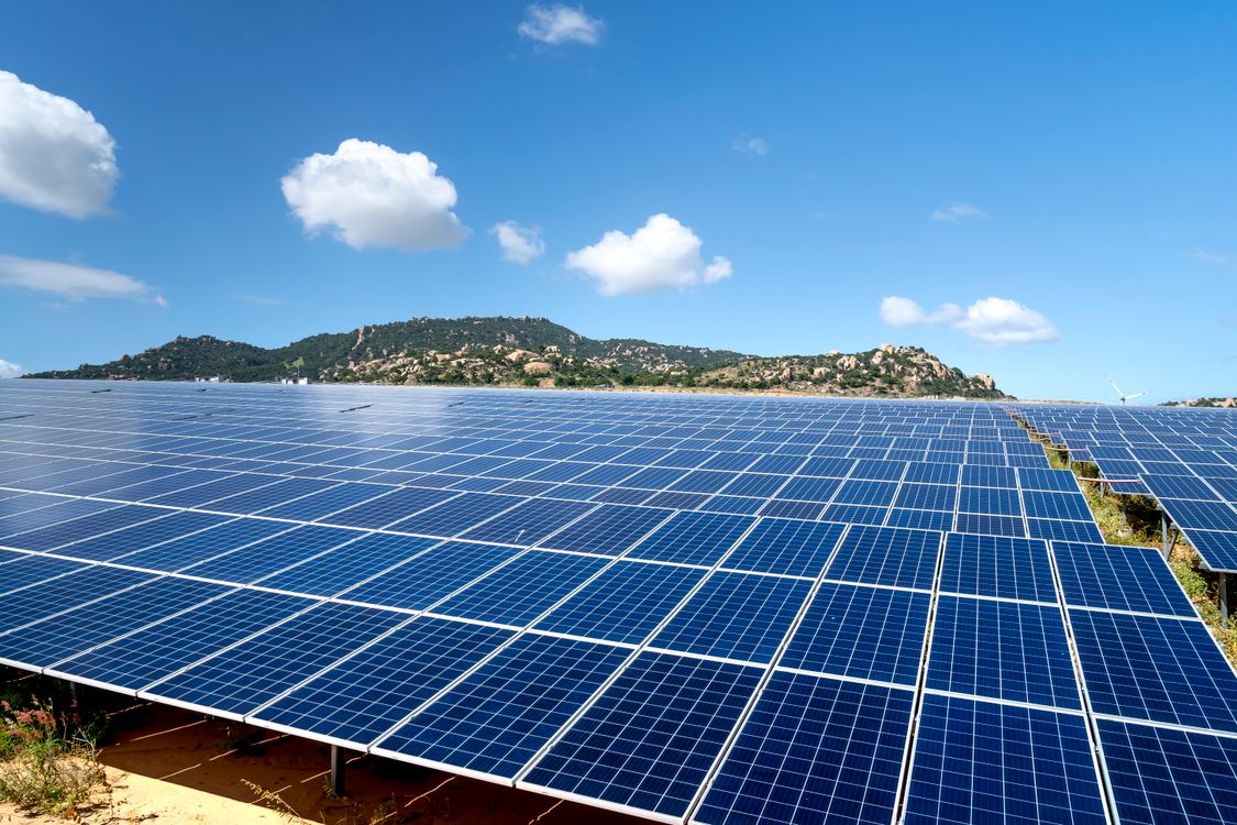 Sprawling solar farm with rows of panels under a blue sky