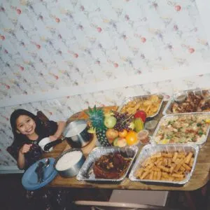 Katherine, age 7, celebrating New Year's Eve with a feast of Filipino foods. It is a New Year's Eve tradition to display 12 round fruits to attract prosperity for the coming year.