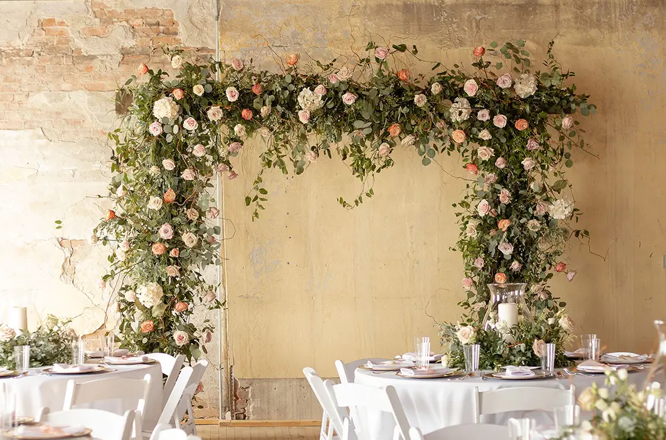 floral square wedding arch against brick and plaster cream wall