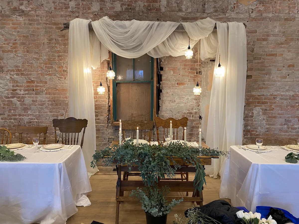 The sweetheart table set beneath chiffon draping and romantic glass lanterns