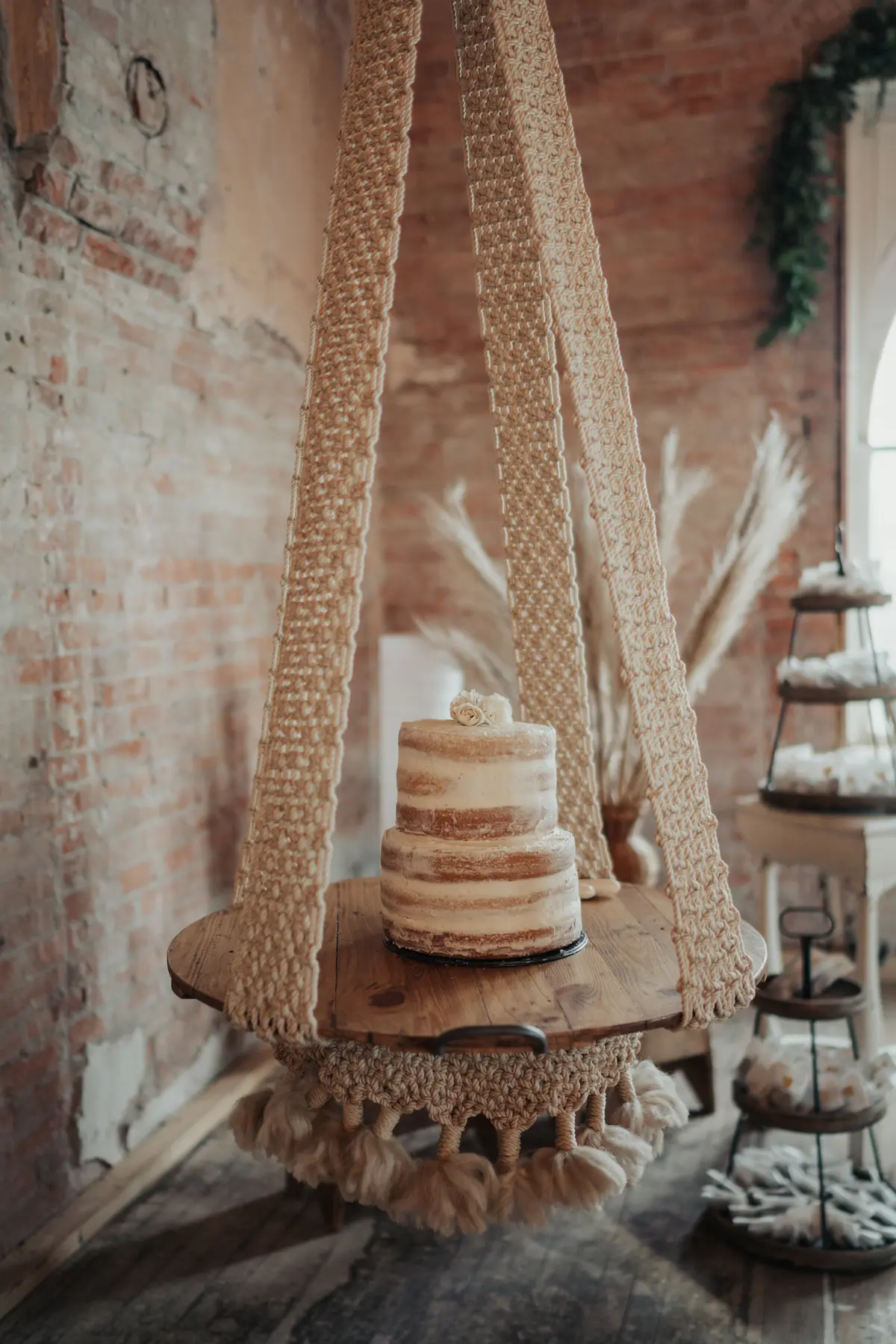 The simple cake sitting on a macrame fixture hanging from the ceiling