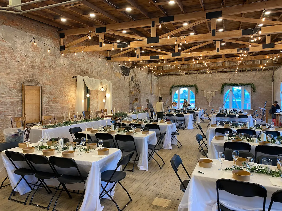 Wide shot of the loft, tables, greenery, and macramé accent between the windows.
