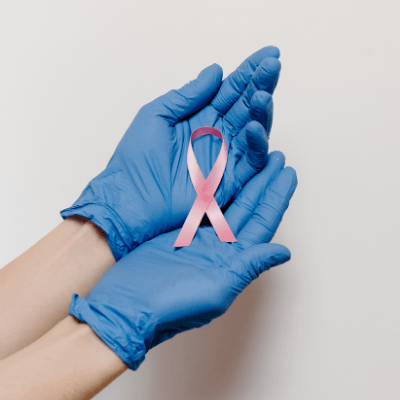 gloved hands hold a breast cancer ribbon