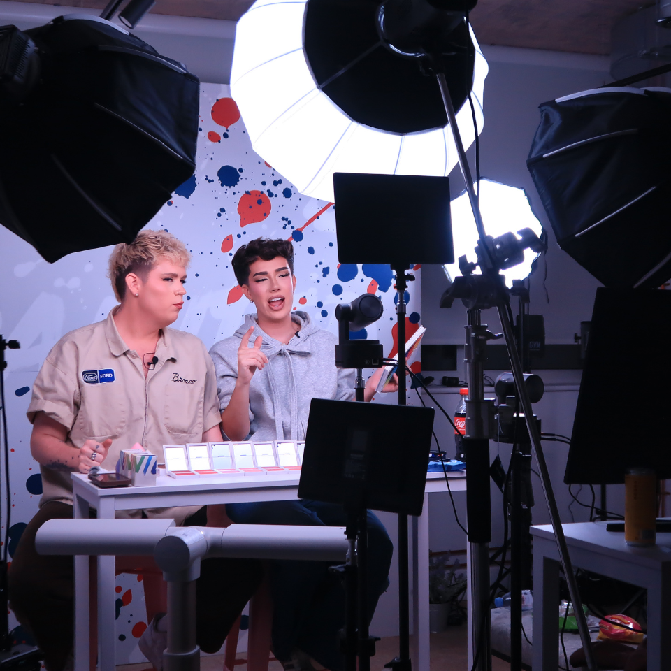 Two people sitting at a table with a camera in front of them.