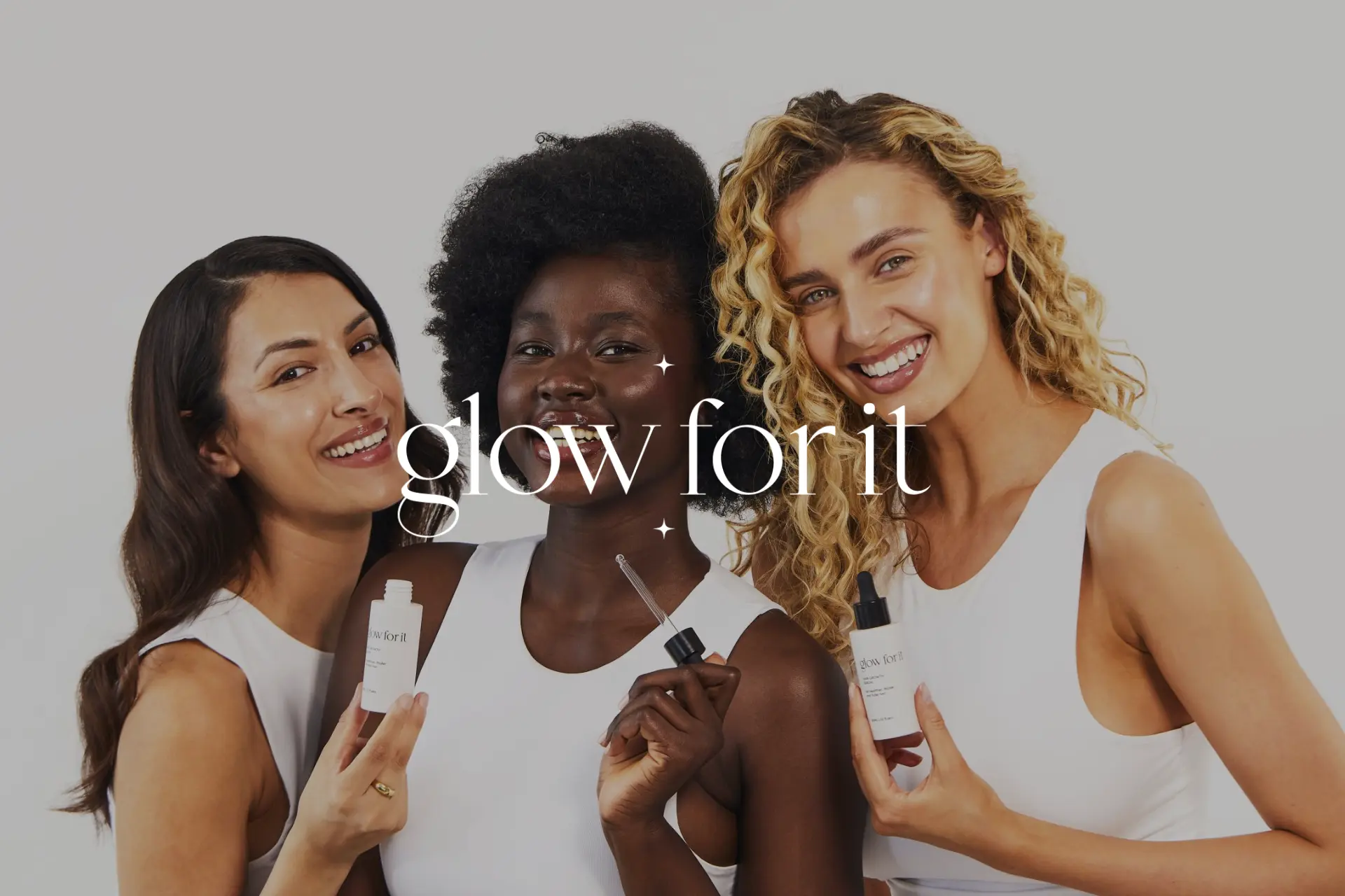 Three women are smiling and holding bottles of Glow for it.