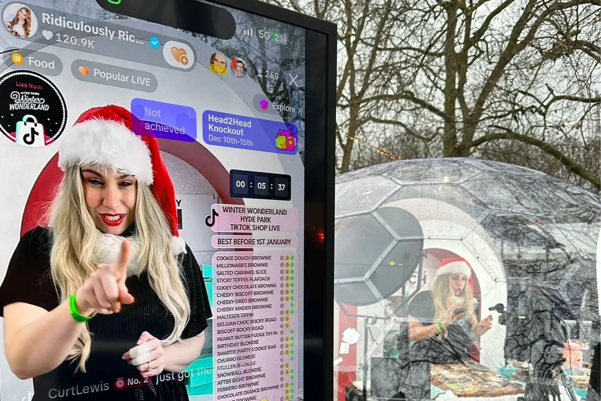 A woman wearing a Santa hat and pointing at a screen.