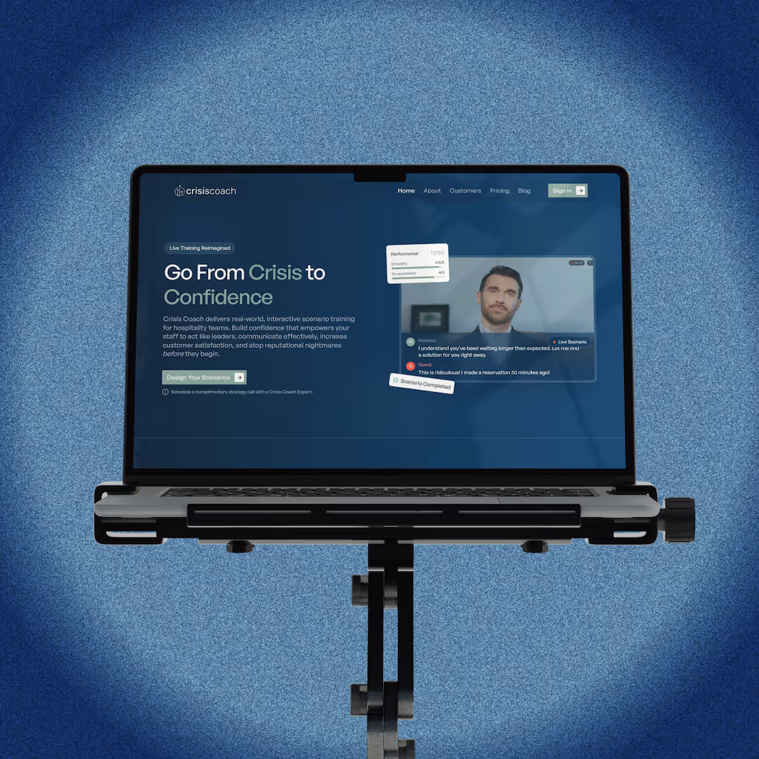 Laptop on a stand displaying Crisis Coach website with training scenario and performance feedback.