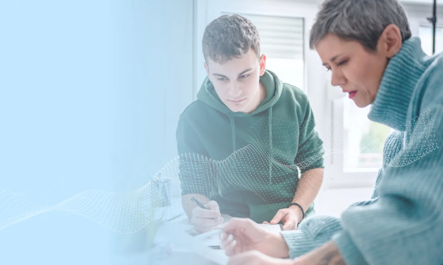 A female administrator at a table with a male student and looking over paperwork.
