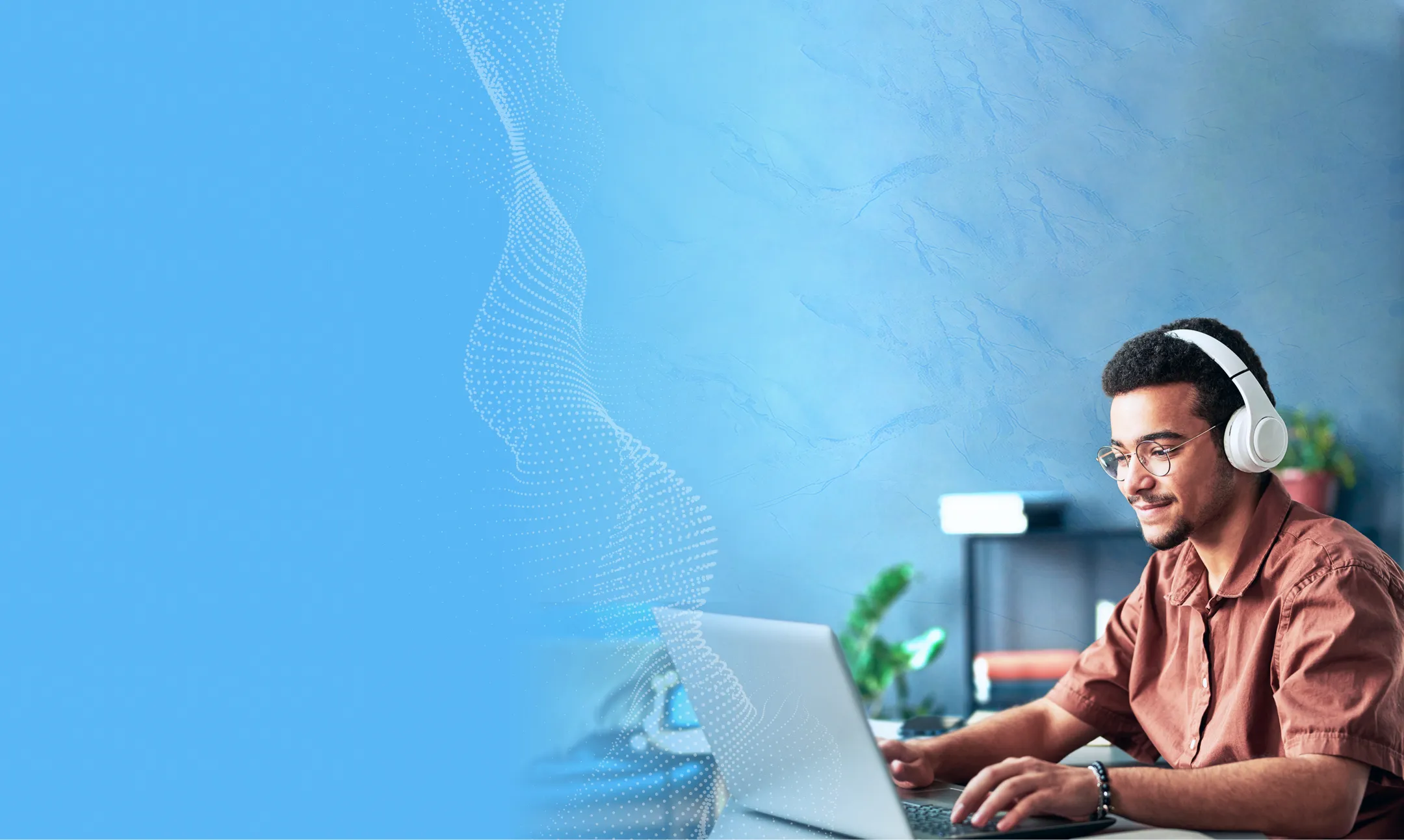 Student male with headphones on and working on a laptop