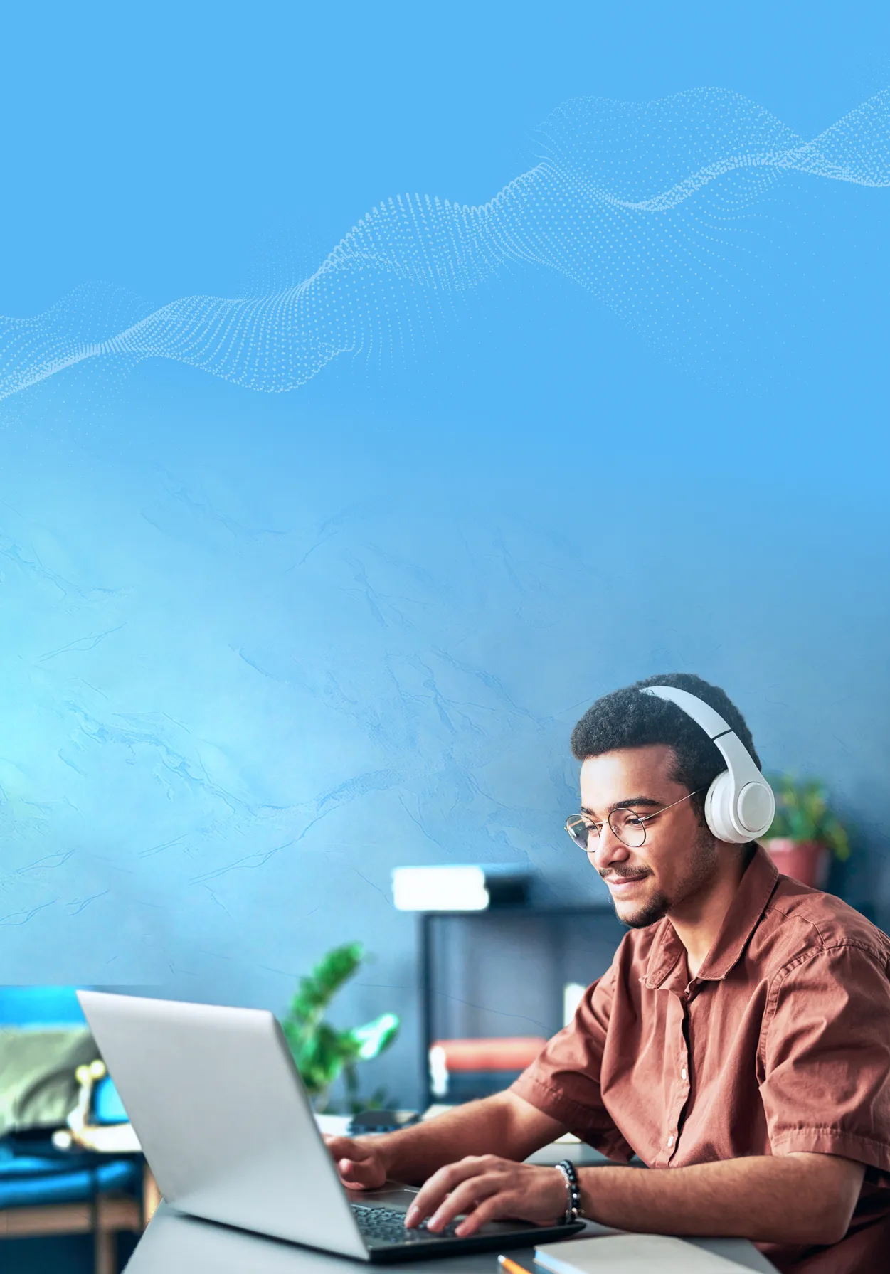 Student male with headphones on and working on a laptop