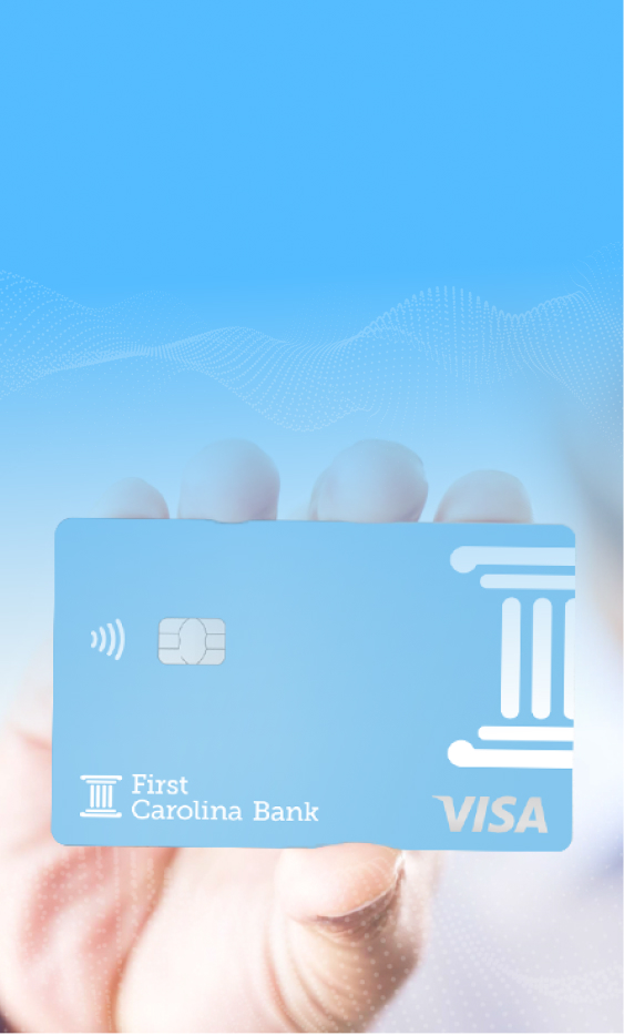 A hand holing up a First Carolina Bank account card.