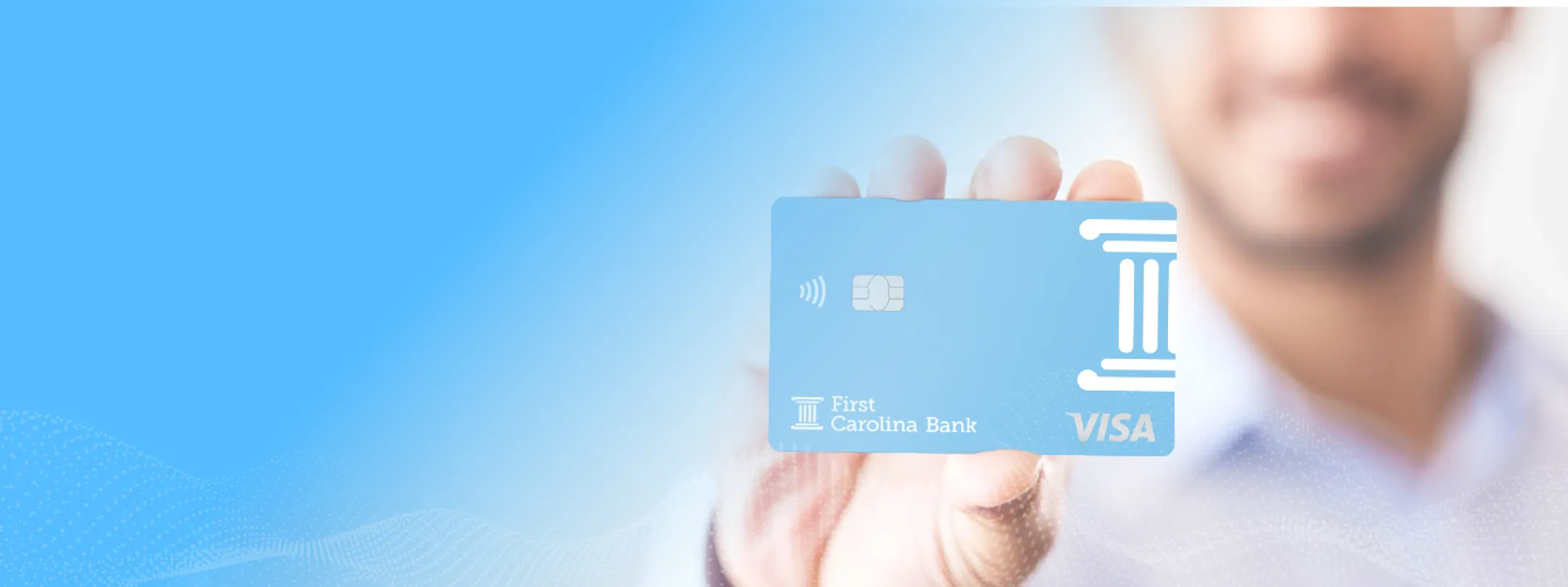 A man holding up a First Carolina Bank Account card.