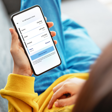 a woman look at her mobile phone with the BankMobile App on the screen.