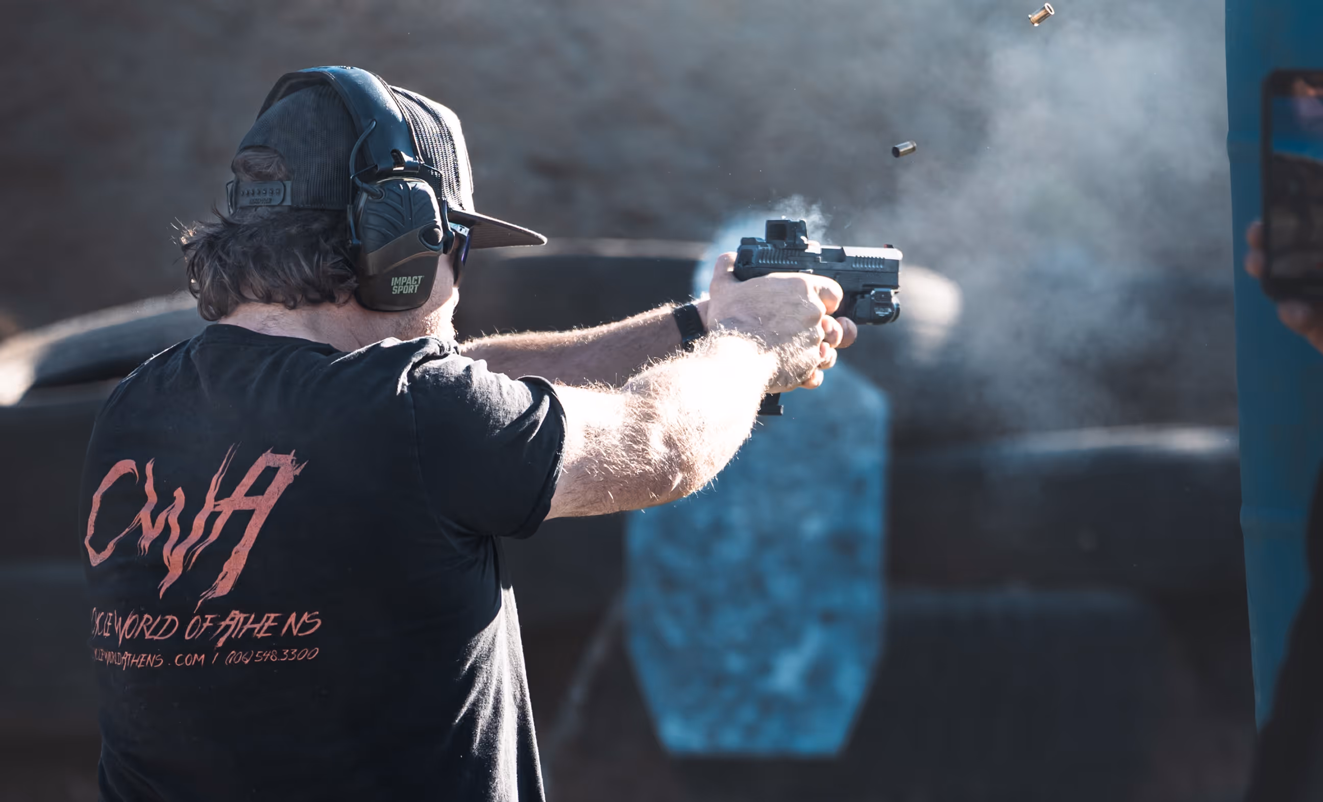 Shooter trains privately in a dynamic pistol course in the Boise, Idaho foothills, captured mid-shot with spent casing and muzzle smoke in frame during a live-fire session at Valiance.