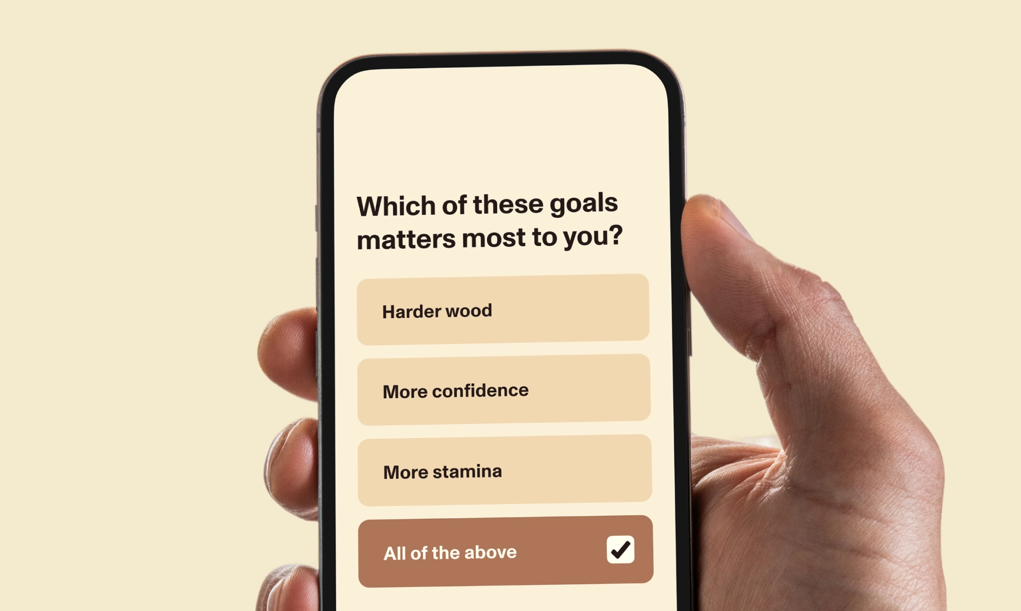A hand holds a phone displaying a survey question reading ‘Which of these goals matters most to you?’ with options for ‘Harder wood,’ ‘More confidence,’ ‘More stamina,’ and ‘All of the above’