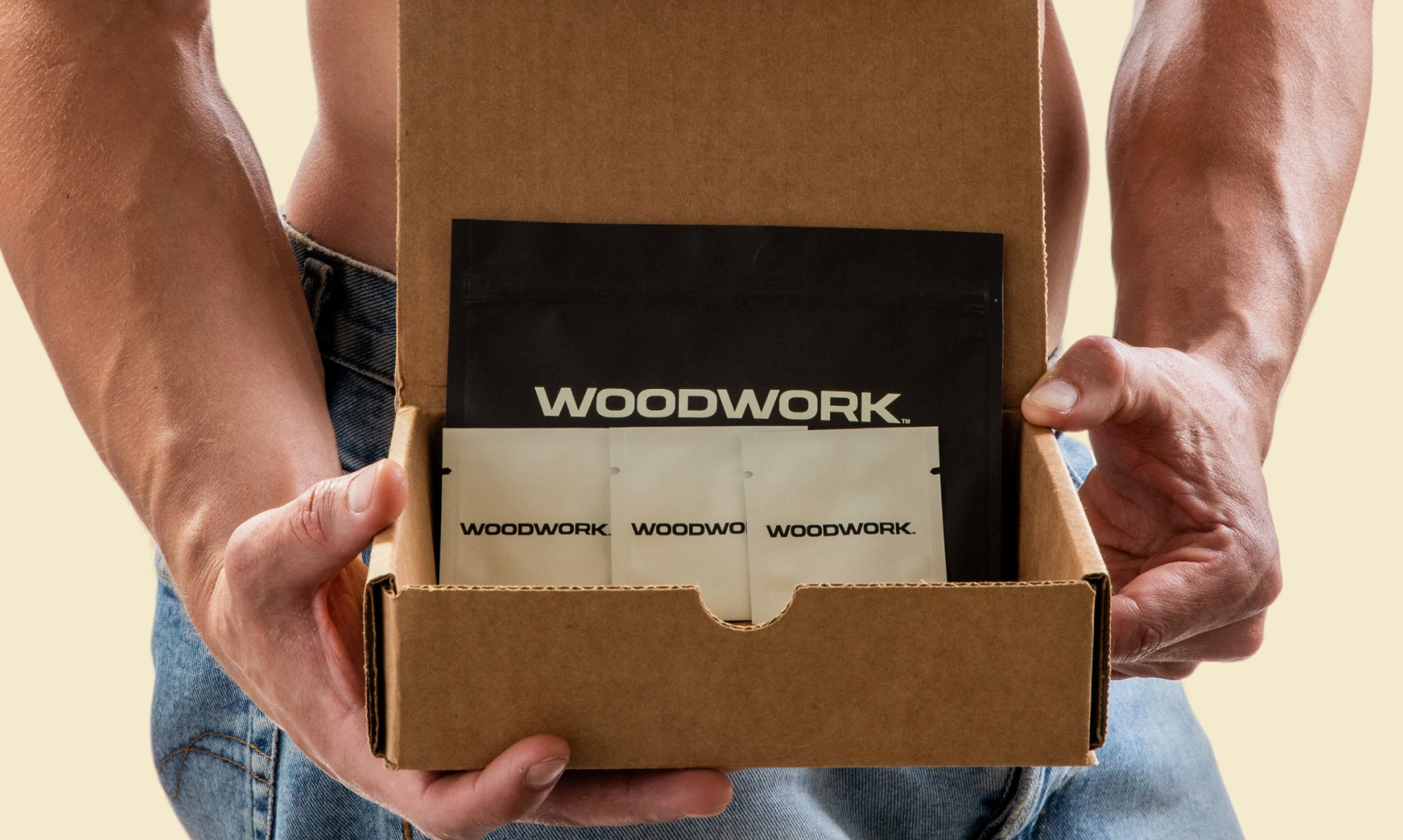 A shirtless man holds an open cardboard box containing Woodwork-branded medication packets