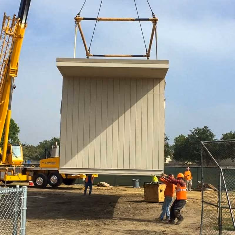 Crane lifting a tan modular section