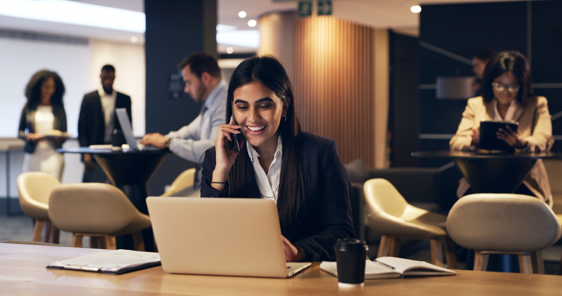 A sales development rep on a call at her laptop in an open-plan office